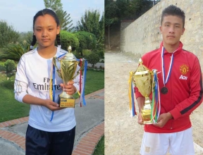 Nepalese girl and boy each with a soccer trophy