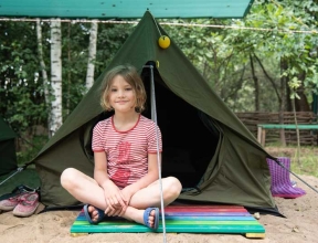 Girl sitting in front of tent at summer camp in Belarus
