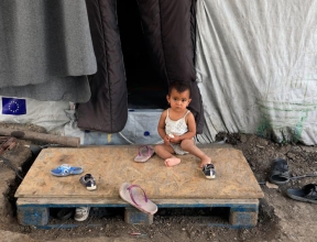 Boy sitting outside of a tent in the refugee camp in Lesvos, Greece