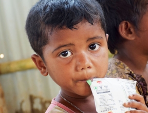 Rohingya child refugee eating a food ration