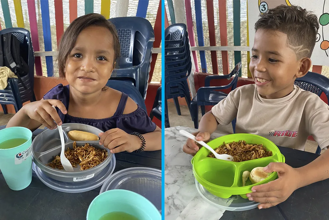 Young boy and girl eating a meal at a child-friendly space in Colombia.