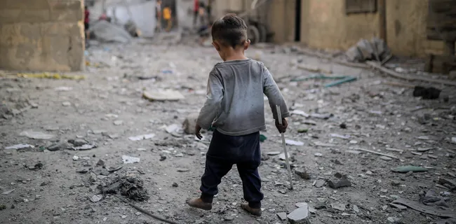 Boy in gaza walking through rubble