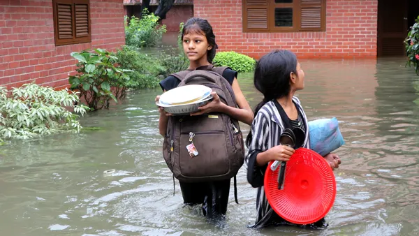 2 girls treading through flood