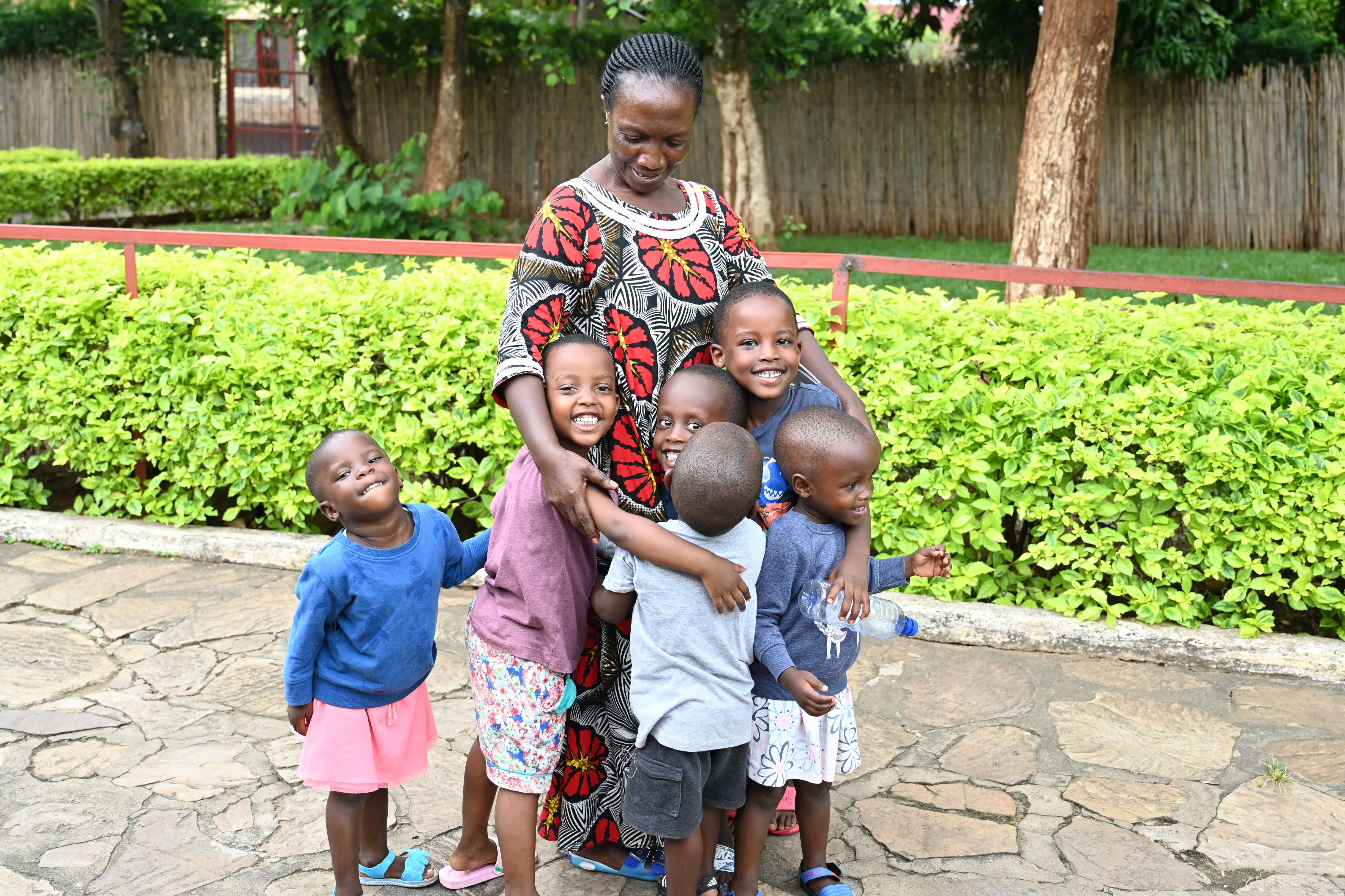 An SOS mother hugs a group of young children in a garden setting in Burundi.