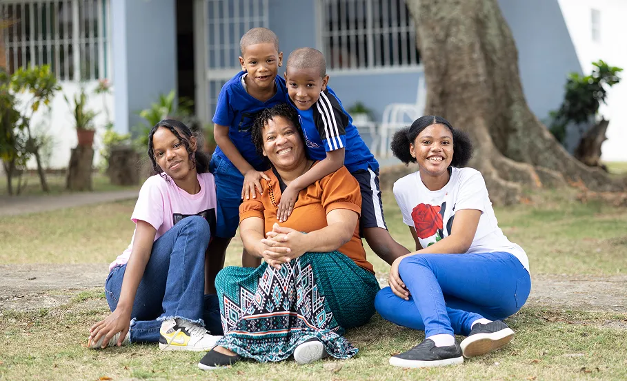 An SOS family in the Dominican Republic sitting together in front of their home smiling