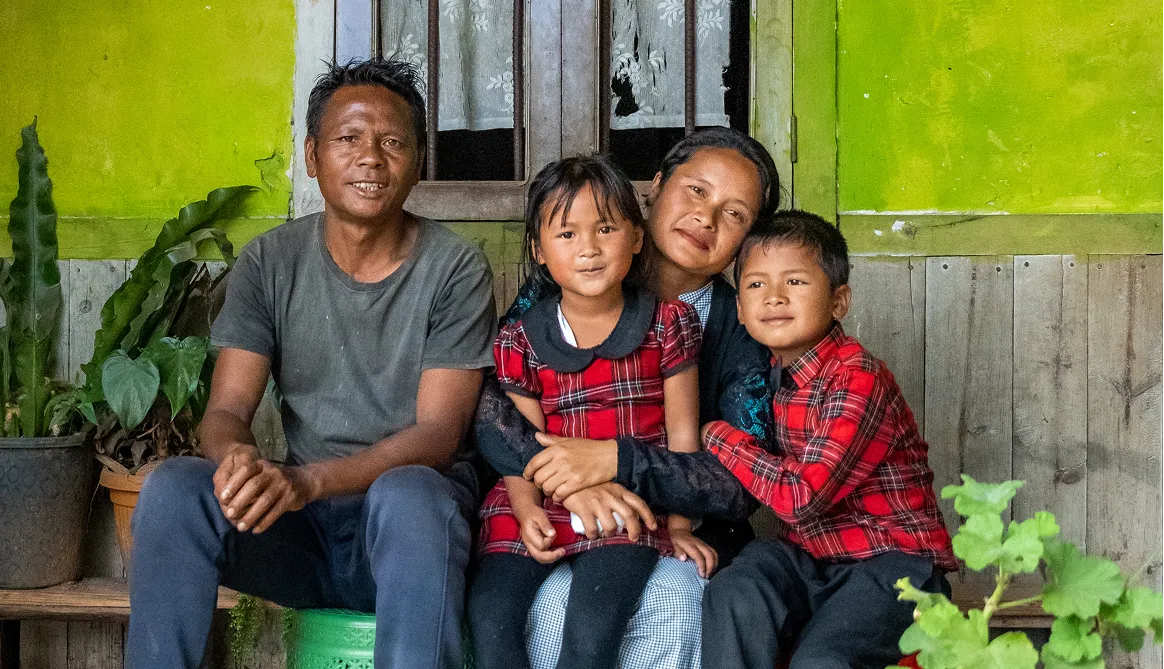 Father, mother and their two children, participants of the SOS Children's Villages Family Strengthening Program, in northern India sitting on their porch.