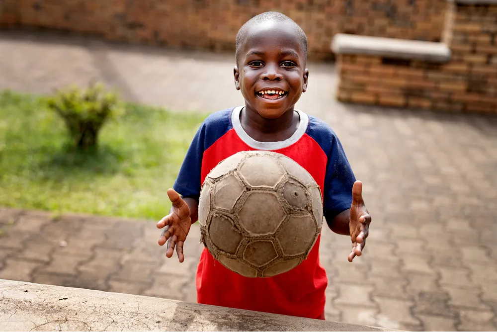 boy playing with a football looking at the camera and smiling