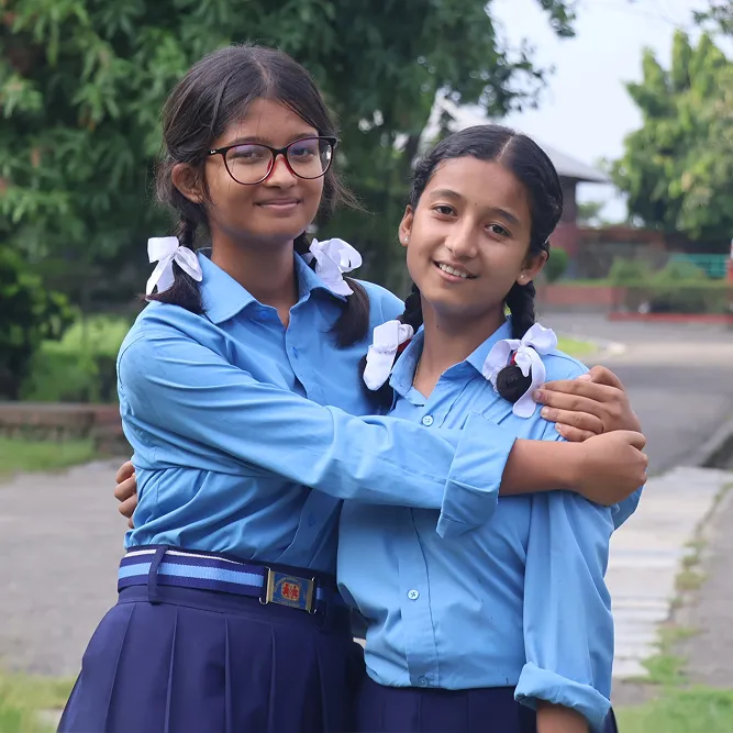 Two girls from Nepal in their school uniforms hugging