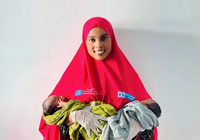 Healthcare worker in Somalia holding two newborns