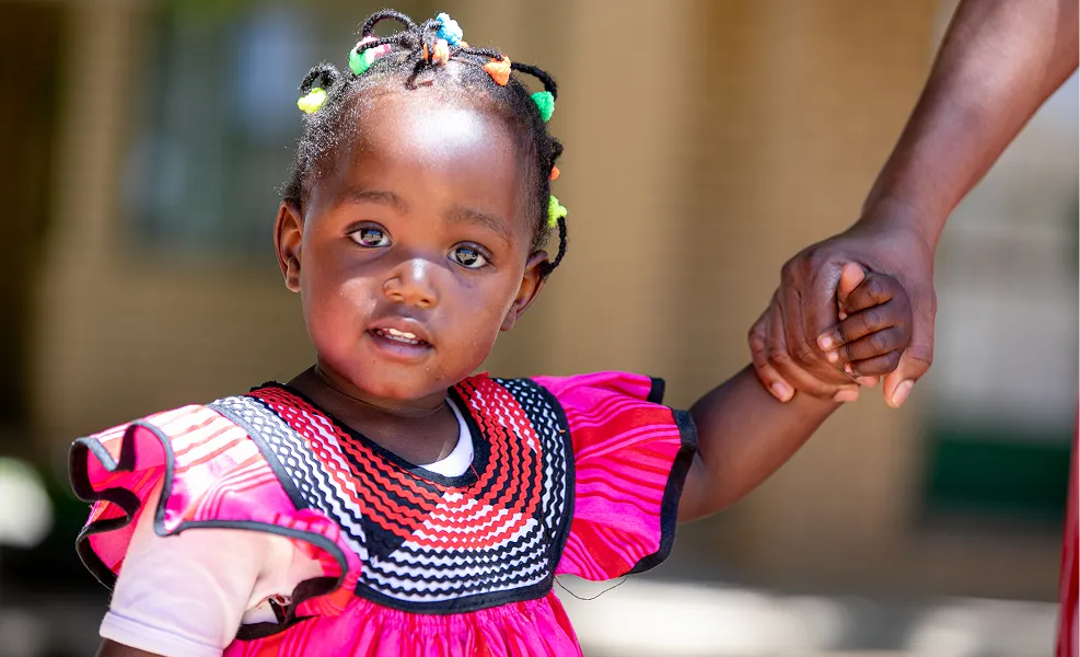 A young girl holding the hand of an adult