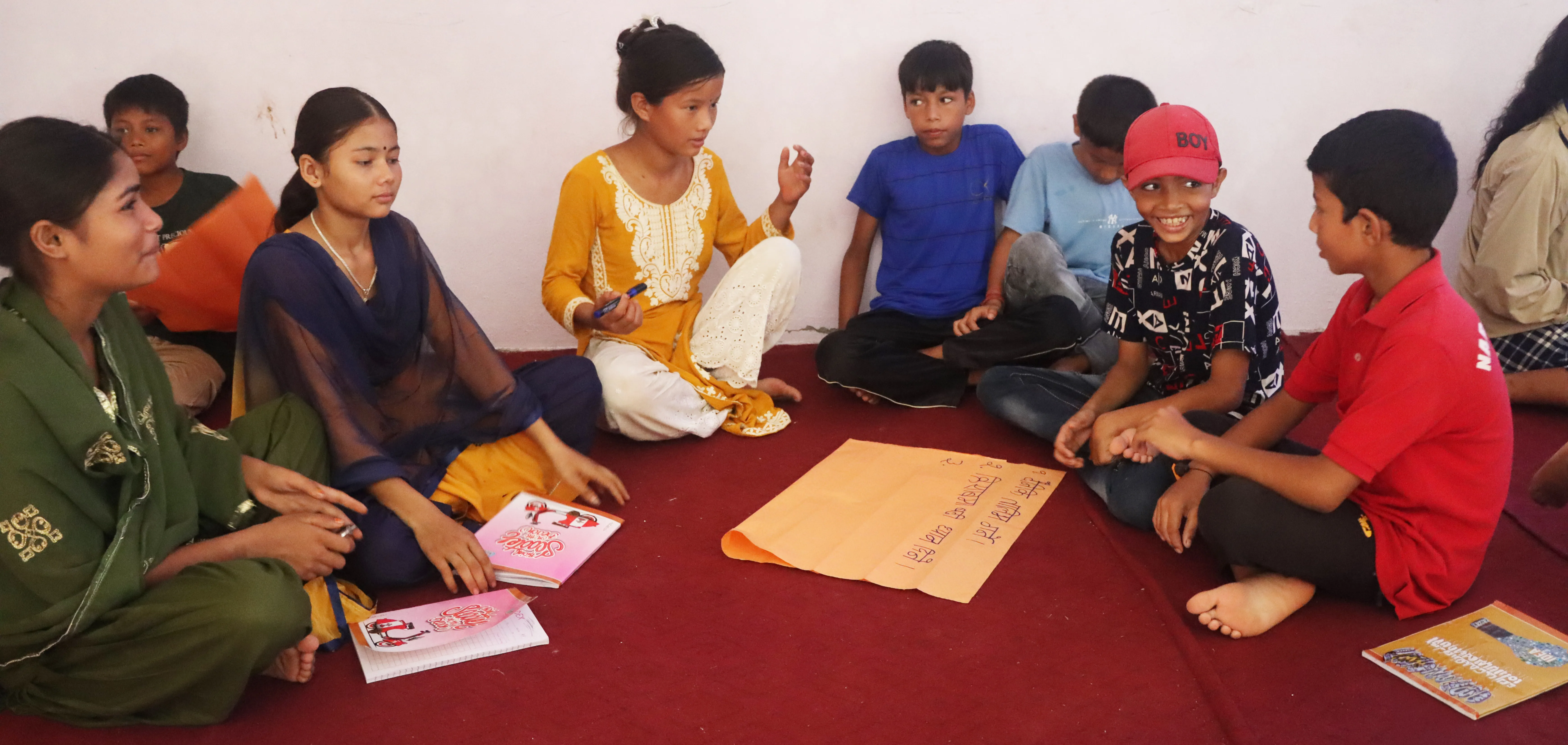 Children sitting together in a children’s club session in Nepal, sharing ideas in a group discussion.
