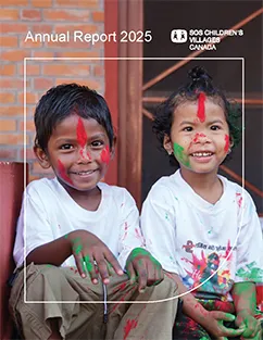 2 young children in Nepal with paint on their faces, hands and clothes, smiling.