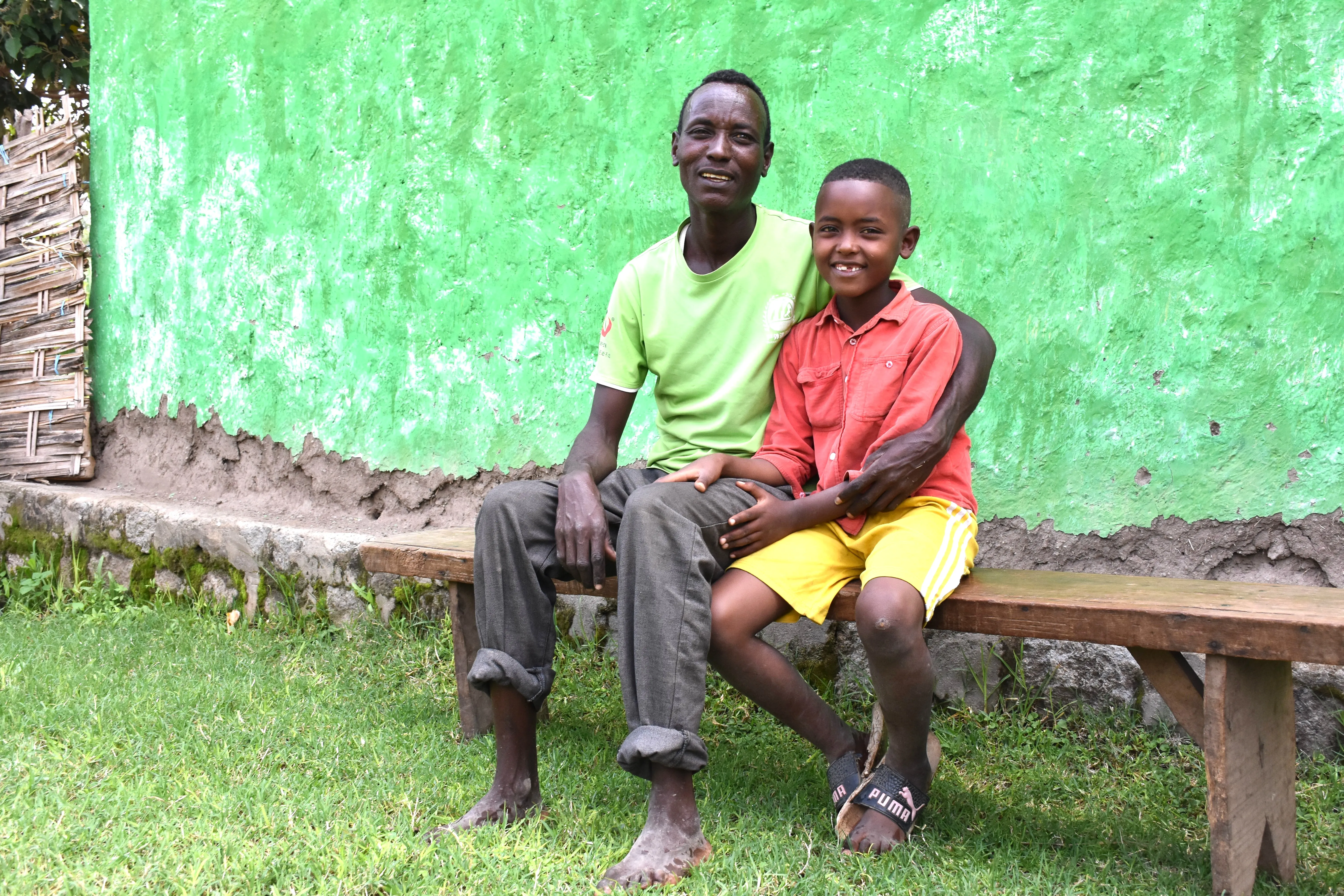Father and son sitting together outside their home in Ethiopia, participants in the SOS Children’s Villages Family Strengthening Program.