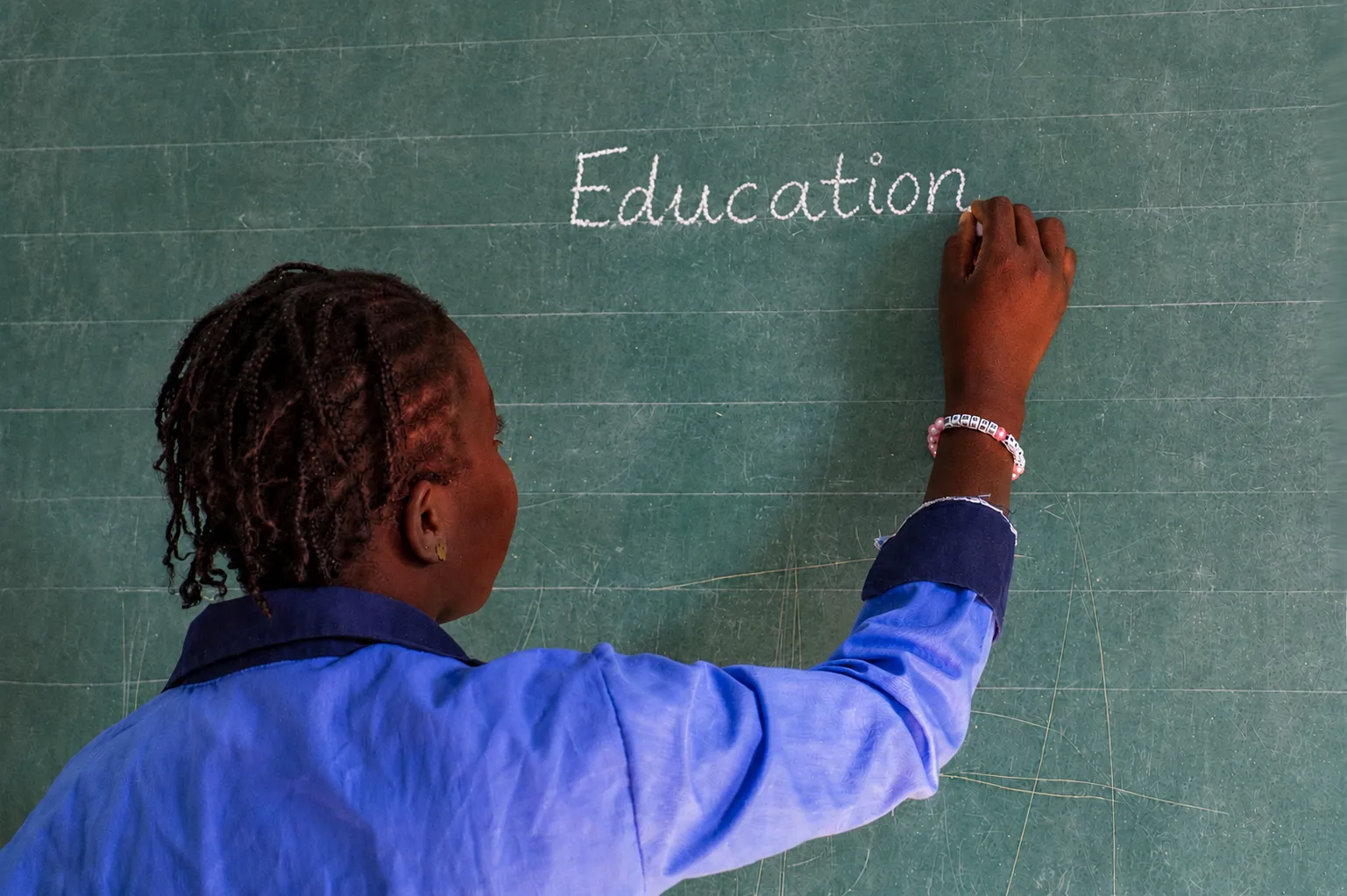 Student writing on a classroom chalkboard during an education activity in West Africa.