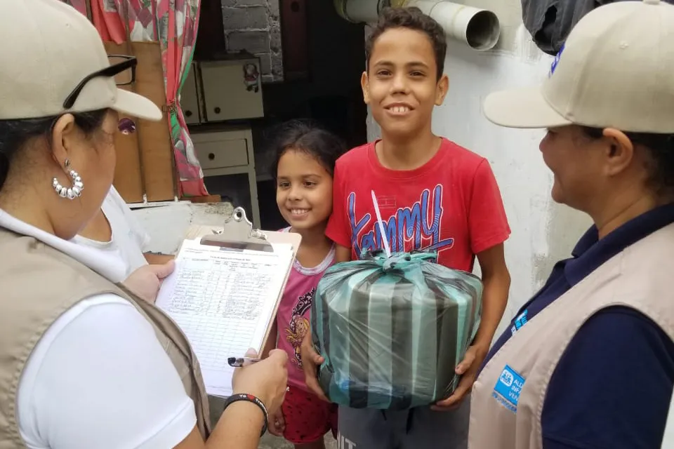 Two children holding essential supplies provided by SOS Children's Villages Venezuela after the devastating earthquake.