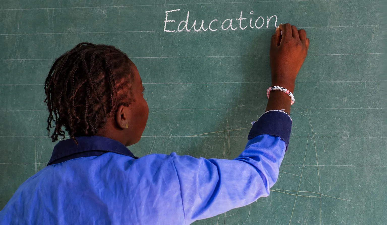 Student writing on a classroom chalkboard during an education activity in West Africa.