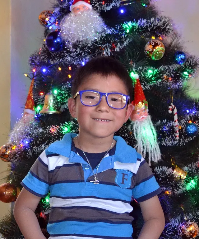 Marco* smiling in front of the Christmas tree