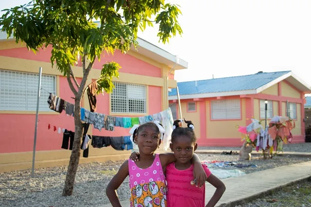 Two smiling SOS children standing in front of their new SOS home.