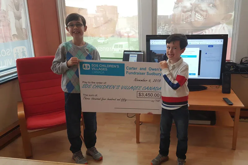 Young brothers presenting their fundraising cheque