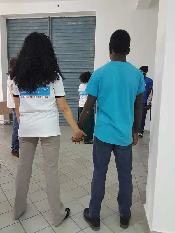 SOS worker holding the hand of a youth refugee in Italy