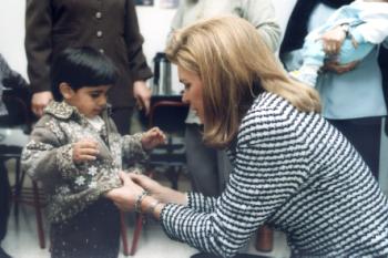 Queen Noor of Jordan helping SOS child with sweater