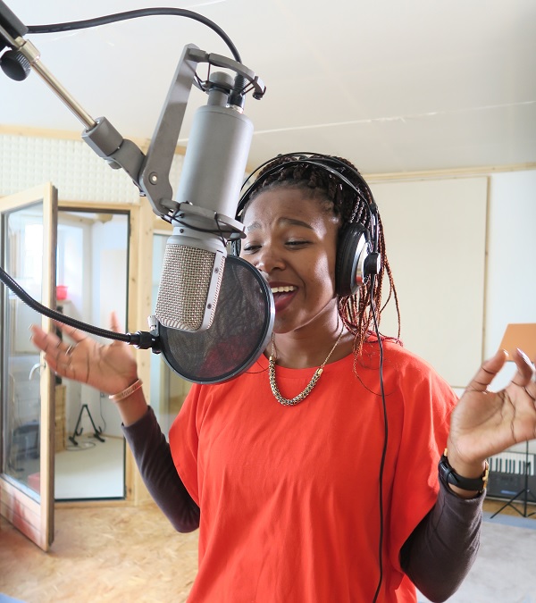 Tumi chantant sa chanson "Thank You" dans un studio d'enregistrement.