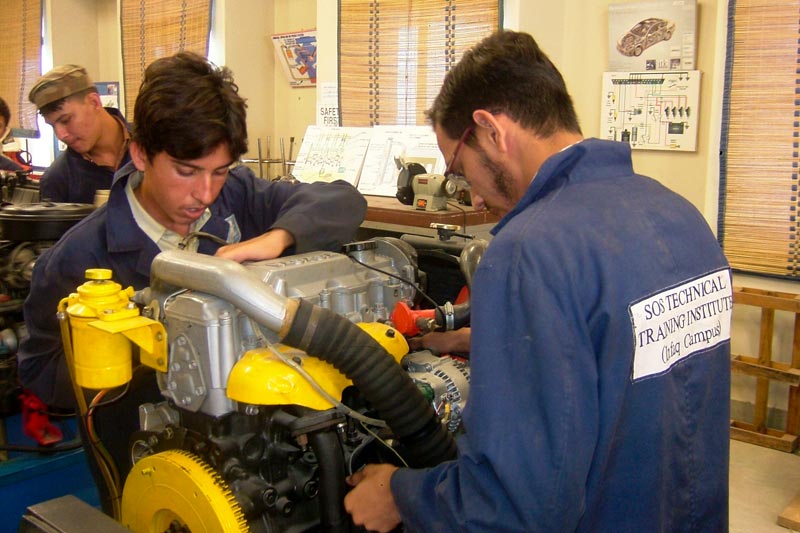 Deux jeunes hommes travaillant sur un moteur au centre de formation professionnelle de Karachi