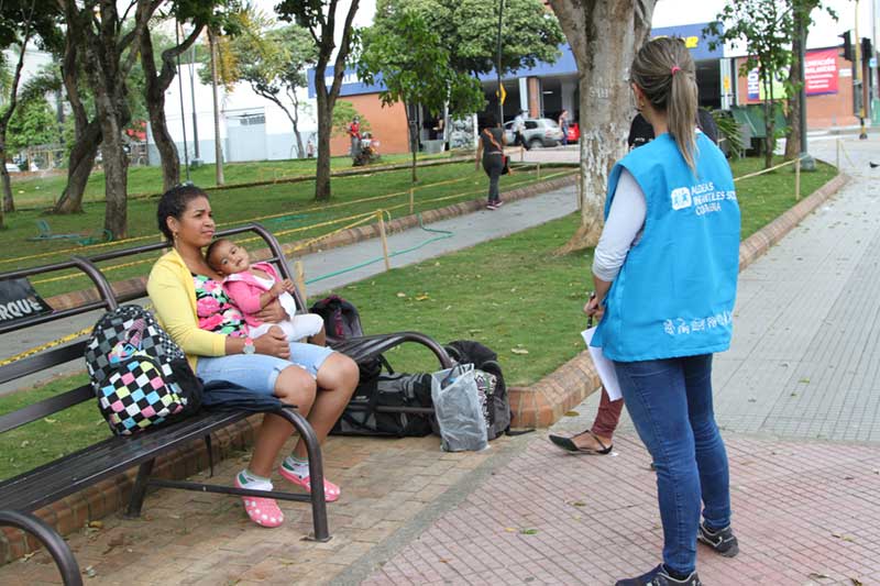 Venezuelan woman holding baby on park bench in Colombia