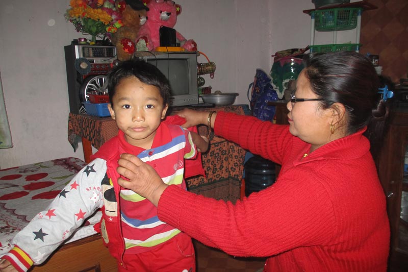 Young boy putting on his jacket